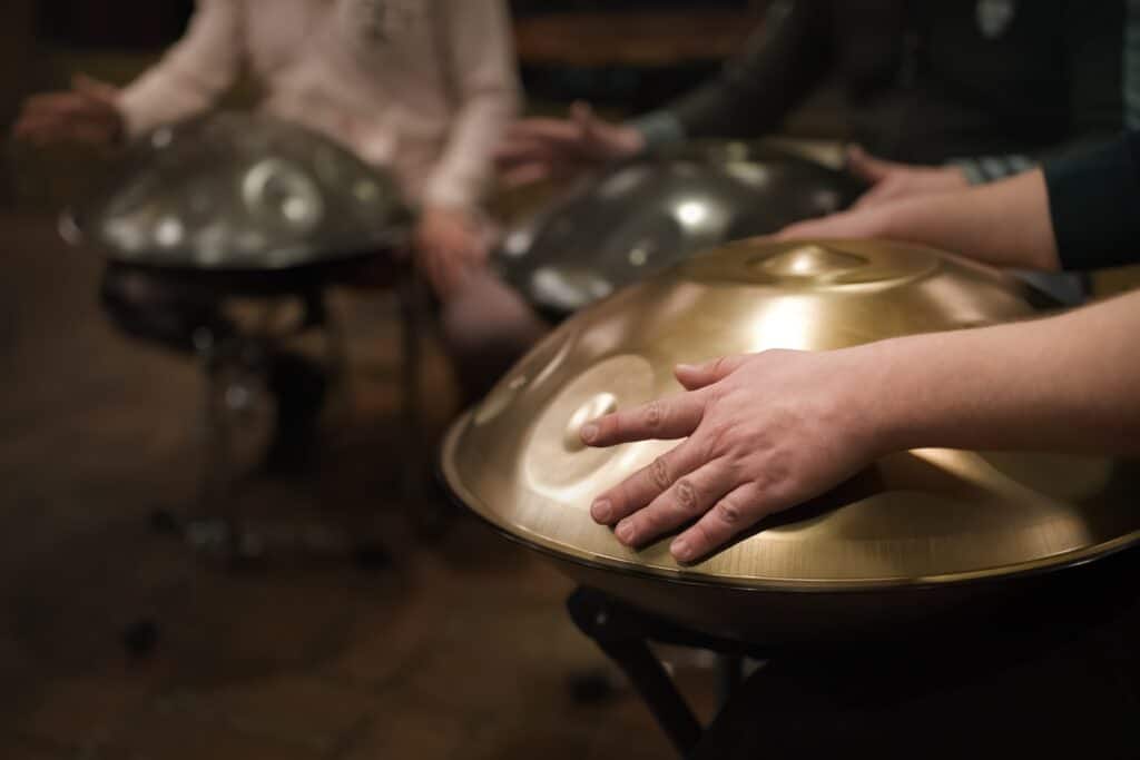 a,musician's,hand,playing,the,handpan,with,other,people.,handpan