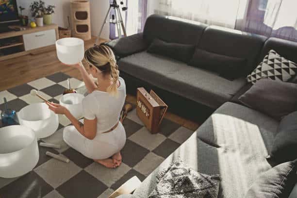 adult woman playing singing crystal bowl at home