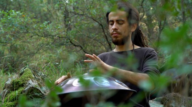 musician playing handpan in forest.