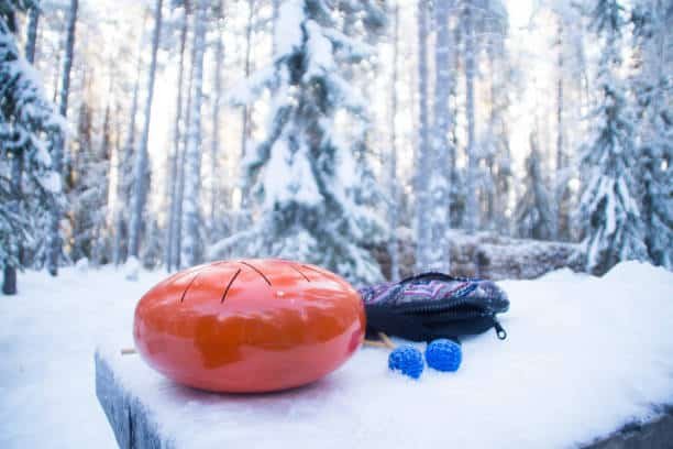 orange steel tongue drum in the winter snowy forest, vaattunki, finland.