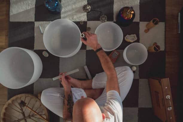 mature man playing singing crystal bowl in his living room.