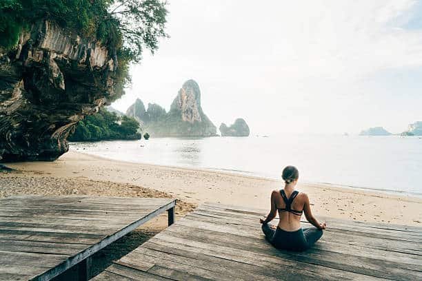 young caucasian woman doing yoga on the pier on the beach in krabi, thailand