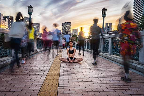 woman meditating into the crowd at sunset