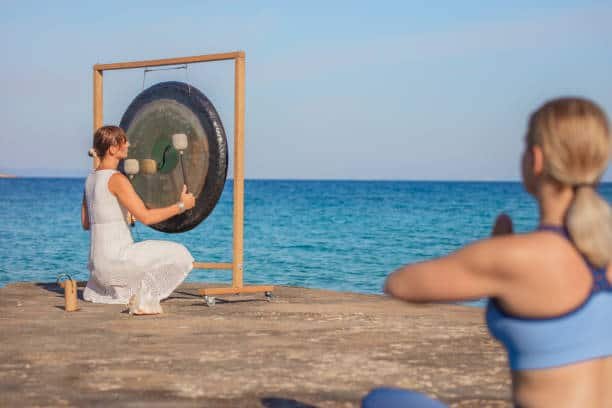 woman doing yoga to sounds of gong on pier at dawn