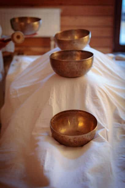 men perform tibetan rituals with sound bowls.