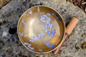 singing bowl made of seven metals with water and floating blue wild flowers